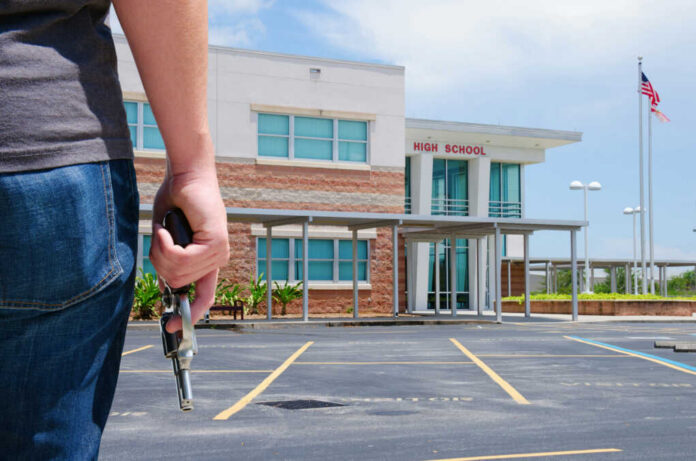 Person holding a handgun outside a high school building
