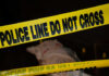 Police tape and covered figure at crime scene