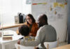 Three people sitting at a desk talking together