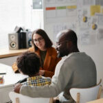 Three people sitting at a desk talking together