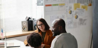 Three people sitting at a desk talking together