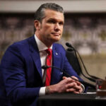Hegseth’s Nonprofit Scandal or Political Smear? Man in suit sitting at a desk with microphone