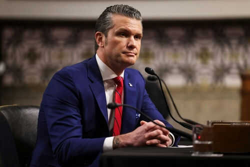 Man in suit sitting at a desk with microphone