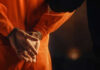 Person in orange jumpsuit with hands cuffed behind back