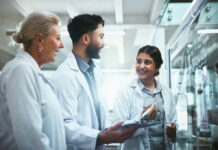 Three scientists discussing notes in laboratory setting