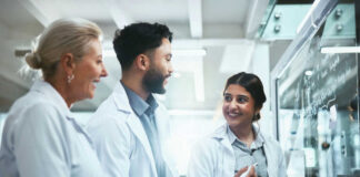 Three scientists discussing notes in laboratory setting
