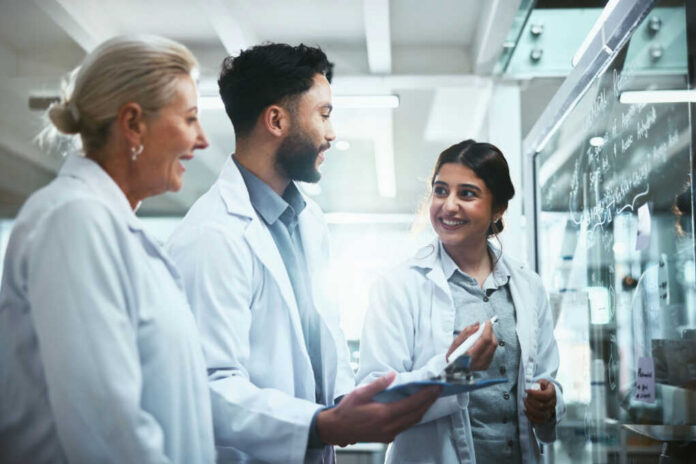 Three scientists discussing notes in laboratory setting