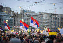 Crowd holding Serbian flags during protest in city
