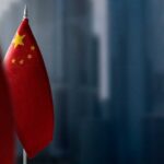 Chinese AI Boast Sparks Pentagon Alarm Close-up of the Chinese flag on a flagpole with a blurred urban background