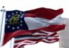 Georgia state flag waving in the wind with an American flag in the background