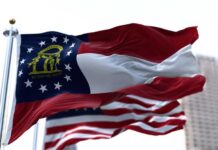 Georgia state flag waving in the wind with an American flag in the background