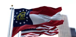 Georgia state flag waving in the wind with an American flag in the background