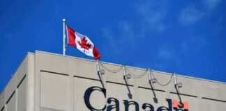 Canadian flag waving atop a building with the word 'Canada' displayed