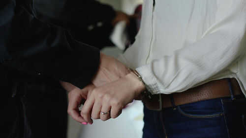 Person in handcuffs wearing jeans and white shirt