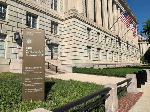 Government building with flags and informational sign outside.