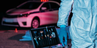 Forensic investigator at crime scene with police car.
