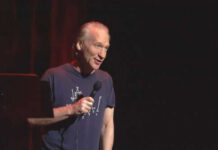 Man holding microphone on stage in dark setting