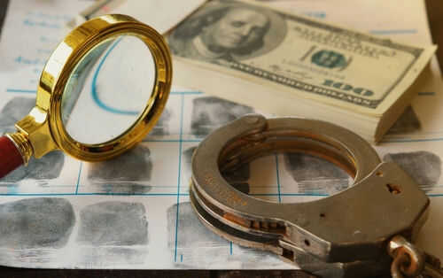 embezzlement2440791319jpg Magnifying glass handcuffs fingerprints money on table