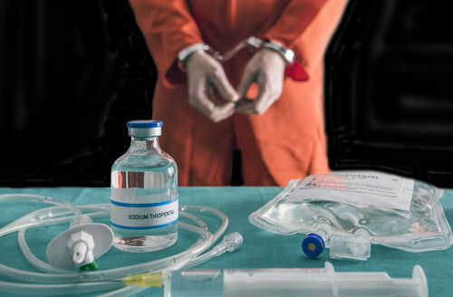 execution762356716 Handcuffed person in orange jumpsuit behind medical equipment