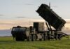 A military missile system positioned on a grassy field during sunset