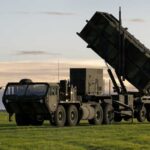 A military missile system positioned on a grassy field during sunset