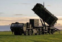 Deep-Strike Push Risks A NATO Firestorm A military missile system positioned on a grassy field during sunset