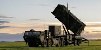 A military missile system positioned on a grassy field during sunset