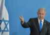 Lebanon Inferno Threat Rattles Washington Man speaking next to Israeli flag.