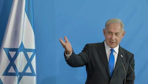netanyahu2276731307 Man speaking next to Israeli flag.