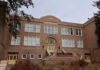 Historic brick school building with arched entrance and large white-framed windows