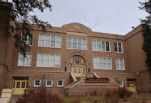 Historic brick school building with arched entrance and large white-framed windows