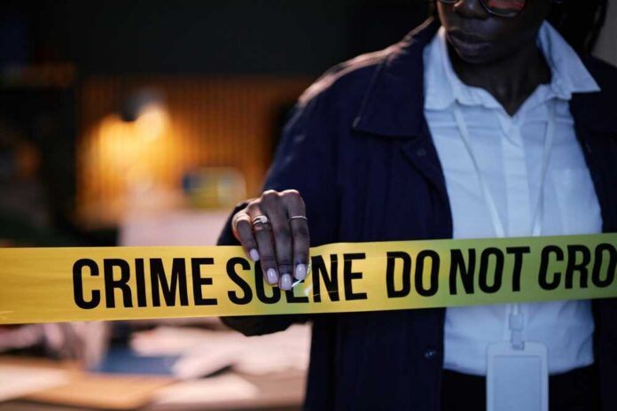 Police,Officer,Seen,Adjusting,Crime,Scene,Tape,During,A,Late-night Police officer holding crime scene tape