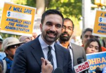 Power Broker Backs America-Is-Disgrace Candidate A man speaking at a rally with supporters holding protest signs