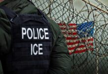 Antifa Terror Plot Nailed By Feds Police officer in tactical gear standing near a barbed wire fence with an American flag in the background