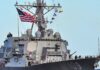 Hormuz Flashpoint: Drones Down, Radar Hit A naval destroyer displaying the American flag and various signal flags