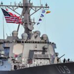 Hormuz Flashpoint: Drones Down, Radar Hit A naval destroyer displaying the American flag and various signal flags