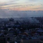 Missiles Fly, Truth Fakes: What Really Hit A city skyline at sunset with smoke rising from buildings