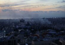 Missiles Fly, Truth Fakes: What Really Hit A city skyline at sunset with smoke rising from buildings