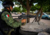 Cartel Ambush Crushed Near Uruapan Soldier aiming machine gun on roadside under a tree.