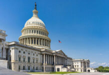 Gotcha Circus Hides Washington’s Failures U.S. Capitol building with American flag, blue sky.
