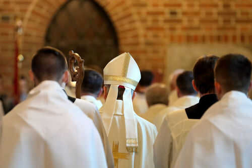bishops653291812 Clerics in white robes facing altar in church