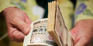 Hands counting a thick stack of Japanese yen banknotes