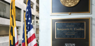 Office plaque beside U.S. and state flags in a government building
