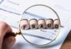 Wire Fraud Trap Springs on Clout Chasers Magnifying glass highlighting wooden blocks spelling fraud on an invoice
