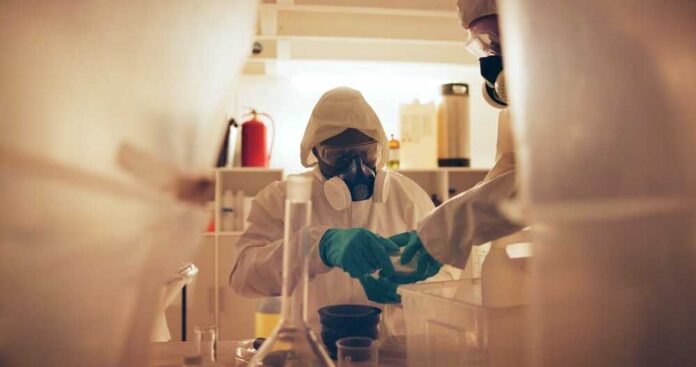Drugs,,People,And,Gas,Mask,In,Lab,For,Production,Of Scientists in protective gear conducting an experiment in a laboratory