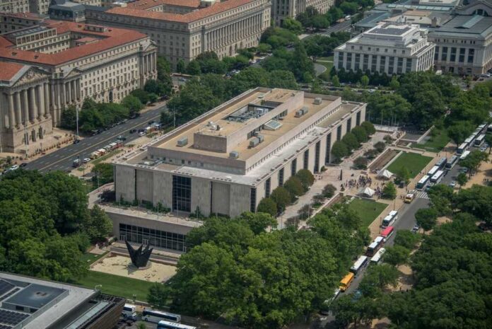 Aerial view of a large modern museum building with surrounding trees and buses