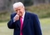 Trump’s Media War Turns Menacing A man in a dark coat and pink tie giving a thumbs up outdoors