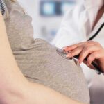 Pregnant woman examined with stethoscope