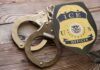 Handcuffs and a police badge on a wooden surface