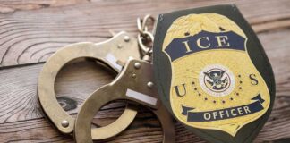 Handcuffs and a police badge on a wooden surface